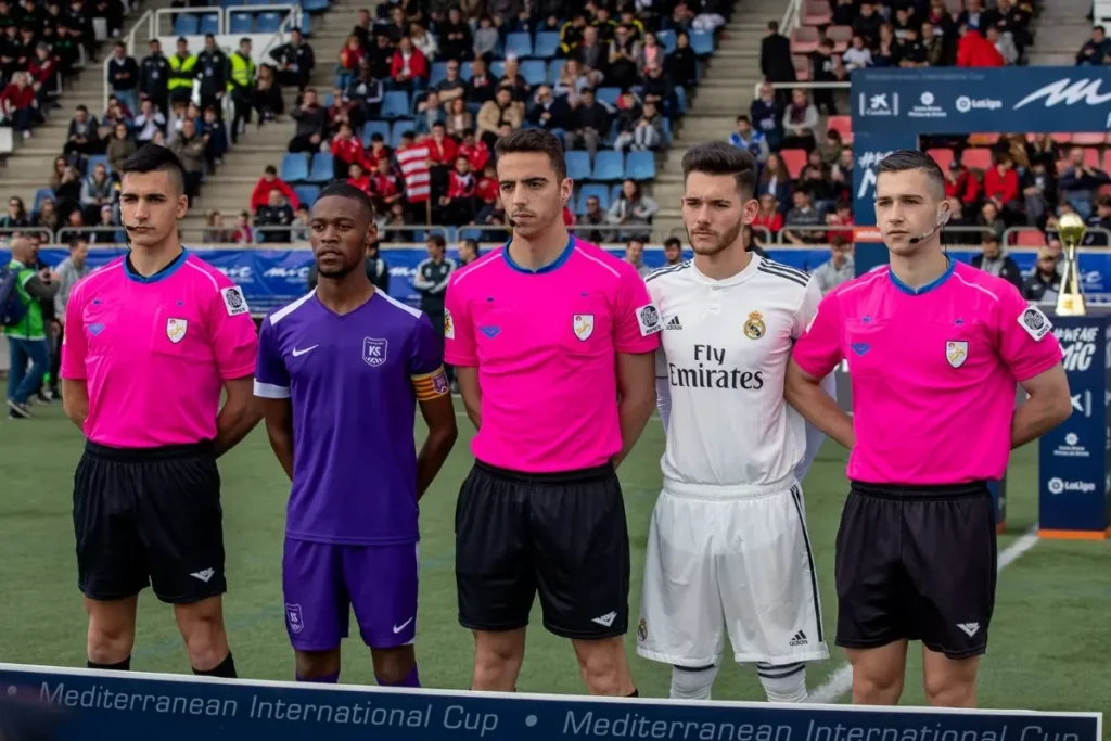 Two team captains—one in Kaptiva kit and one in a white Real Madrid kit—before a match at the Mediterranean International Cup.